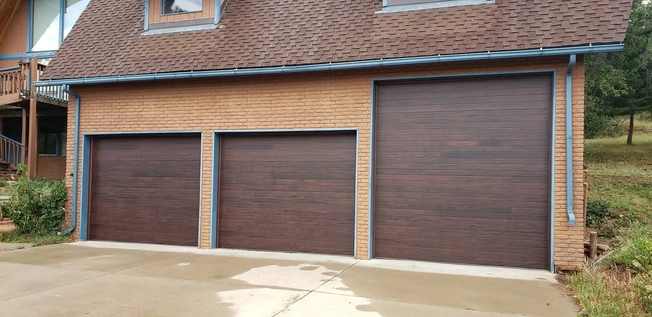 Three-car garage door installation on brick home — Swain Garage Doors Brighton CO