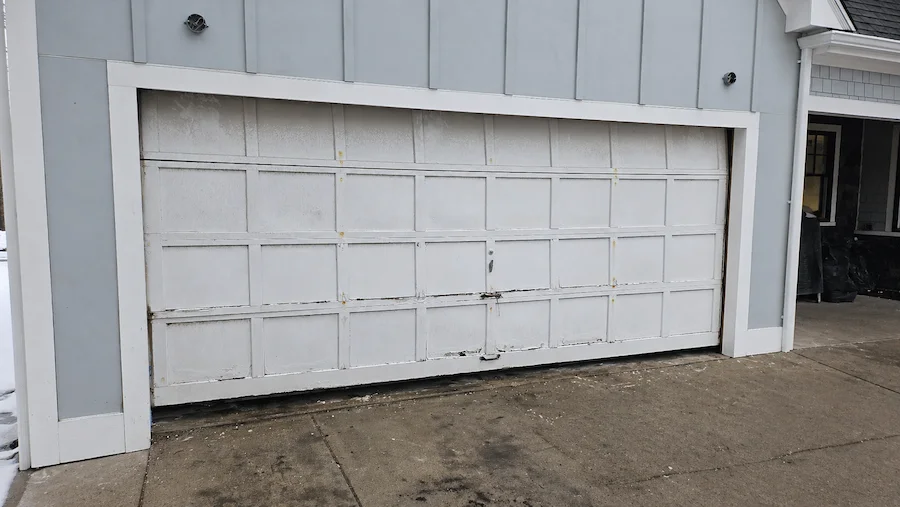 Old garage door before replacement — worn white panels on Denver area home