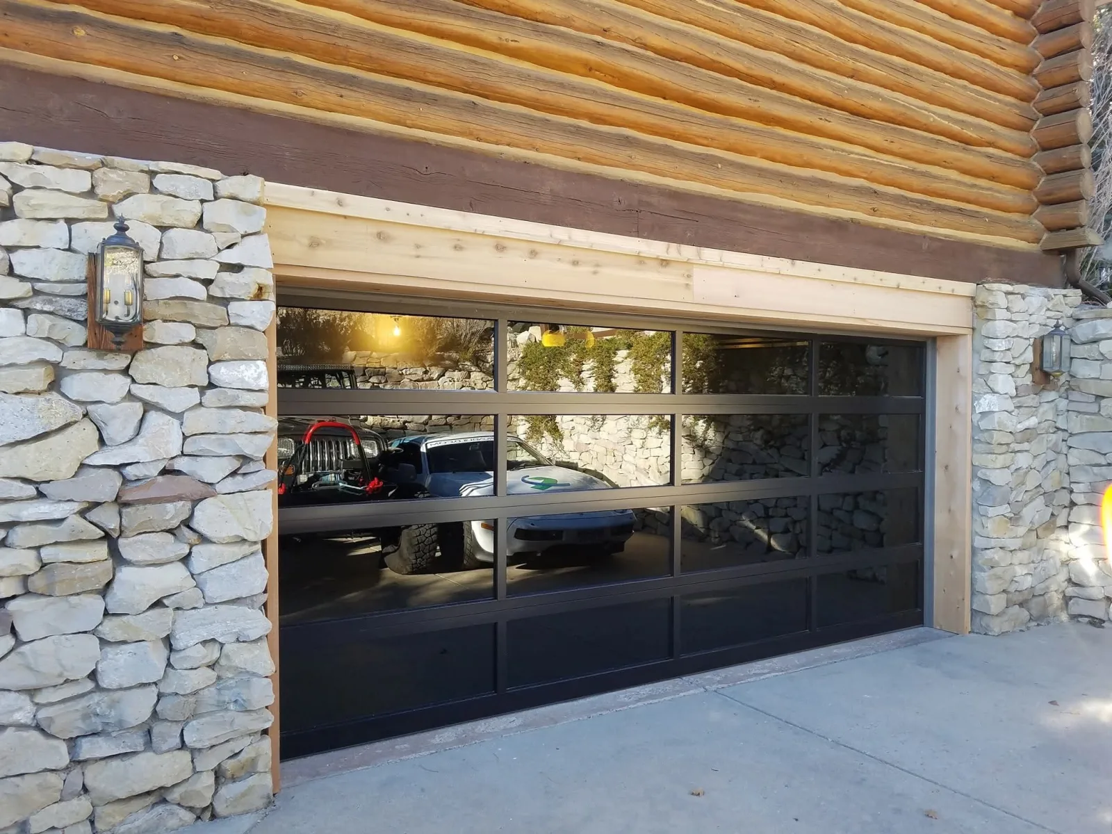 Modern glass panel garage door on stone home