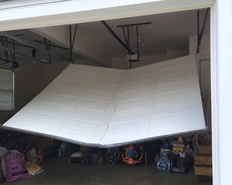 Garage door off track with bent panel inside Denver Colorado garage